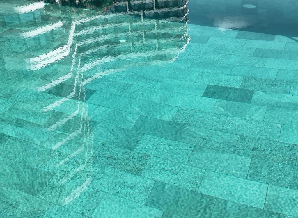 Skatiena uz skaidru ūdeni ar akmens flīzēm, kurā atspoguļojas apkārtējā vide. Ideāla ainava atpūtai un relaksācijai.