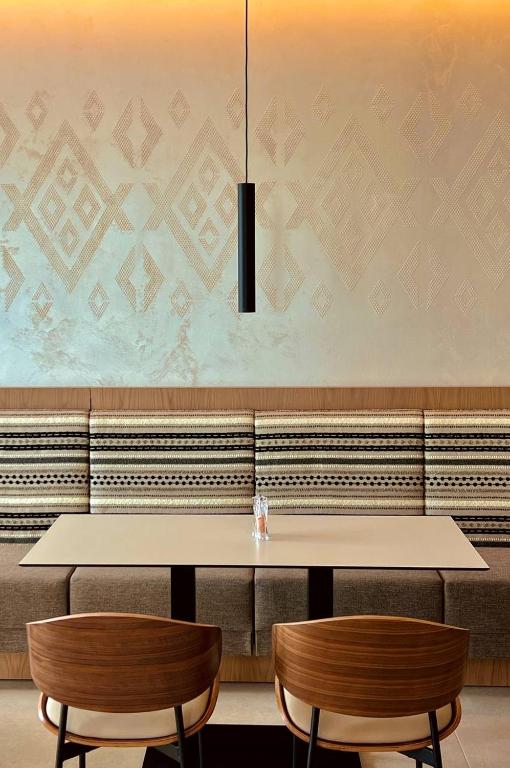 Mūsdienīgs restorāna interjers ar stilīgu apgaismojumu, kas izceļ elegantas sienas dekorācijas un komfortablu sēdvietu. Viegla un gaumīga atmosfēra, ideāli piemērota maltītēm un atpūtai.