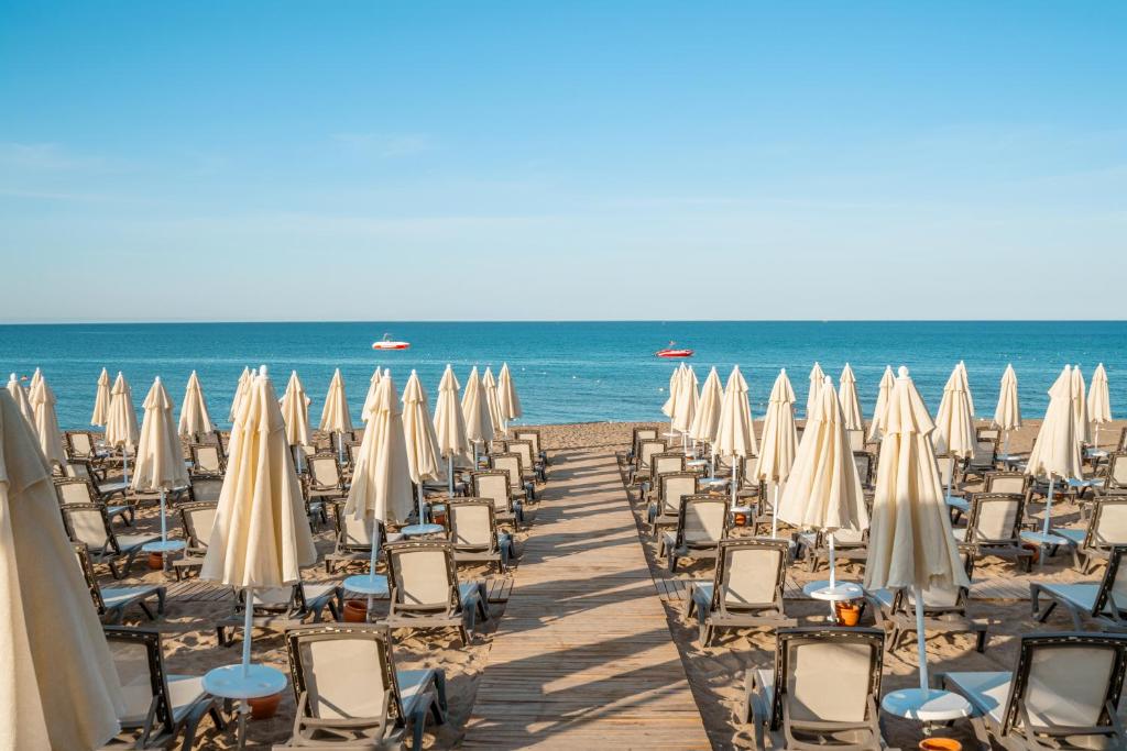 Vox Maris Resort pludmale ar sauļošanās krēsliem un lietussargiem pie jūras