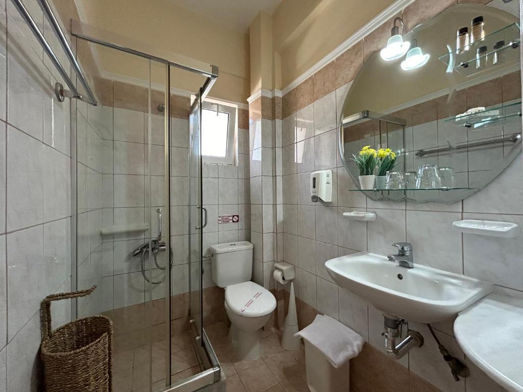 Moderns vannas istabas interjers ar stikla dušu, tualeti un izlietni, kas papildināts ar dekoratīvām detaļām. Ideāli piemērots viesnīcu vai mājokļu vajadzībām.