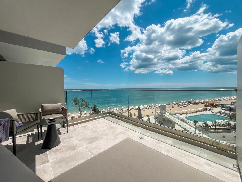 Mūsdienīgs balkons ar skatu uz pludmali un jūru, kurā redzama atpūtas zona un baseins. Ideāla vieta relaksācijai saulainā dienā.
