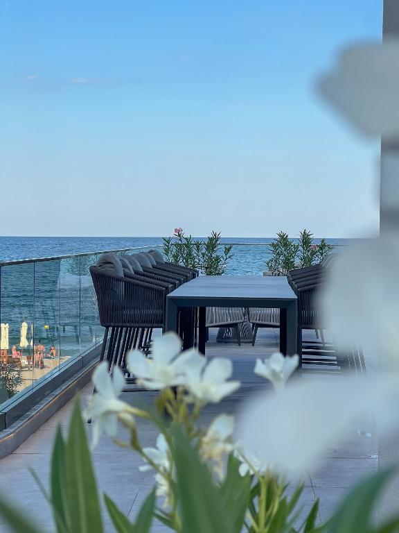Terase ar skatu uz jūru, kurā redzams galds un krēsli, apzaļumoti augi un ziedi. Ideāla vieta relaksācijai un baudīšanai.