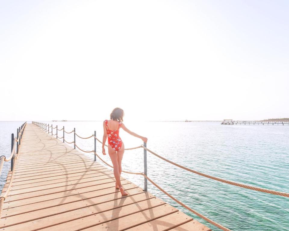 Sieviete sarkanos peldkostīmos pie koka piestātnes pie Pickalbatros Laguna Vista Beach.