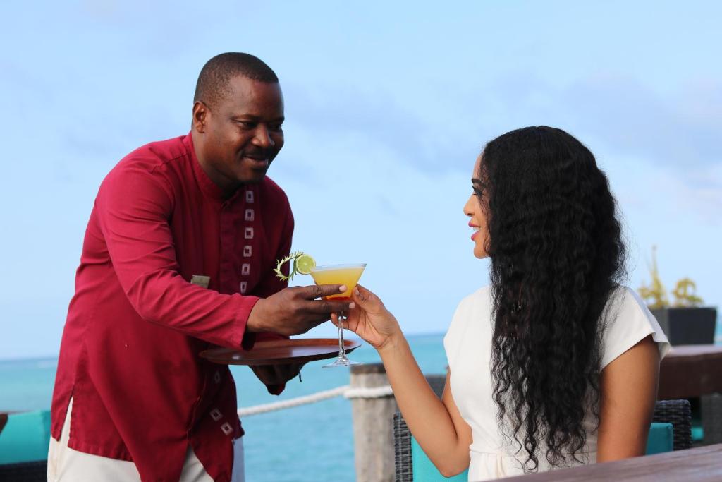 Essque Zalu Zanzibar viesnīcas personāls pasniedz dzērienu piekrastē.