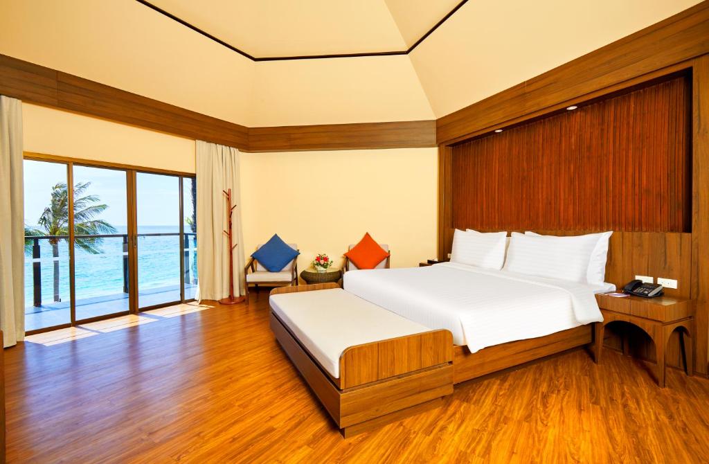 Mūsdienīgs viesnīcas numurs ar plašām logu durvīm, kas paver skatu uz jūru, un koka grīdu. Numurā ir divguļamā gulta un atpūtas zona ar krēsliem un ziedu kompozīciju.