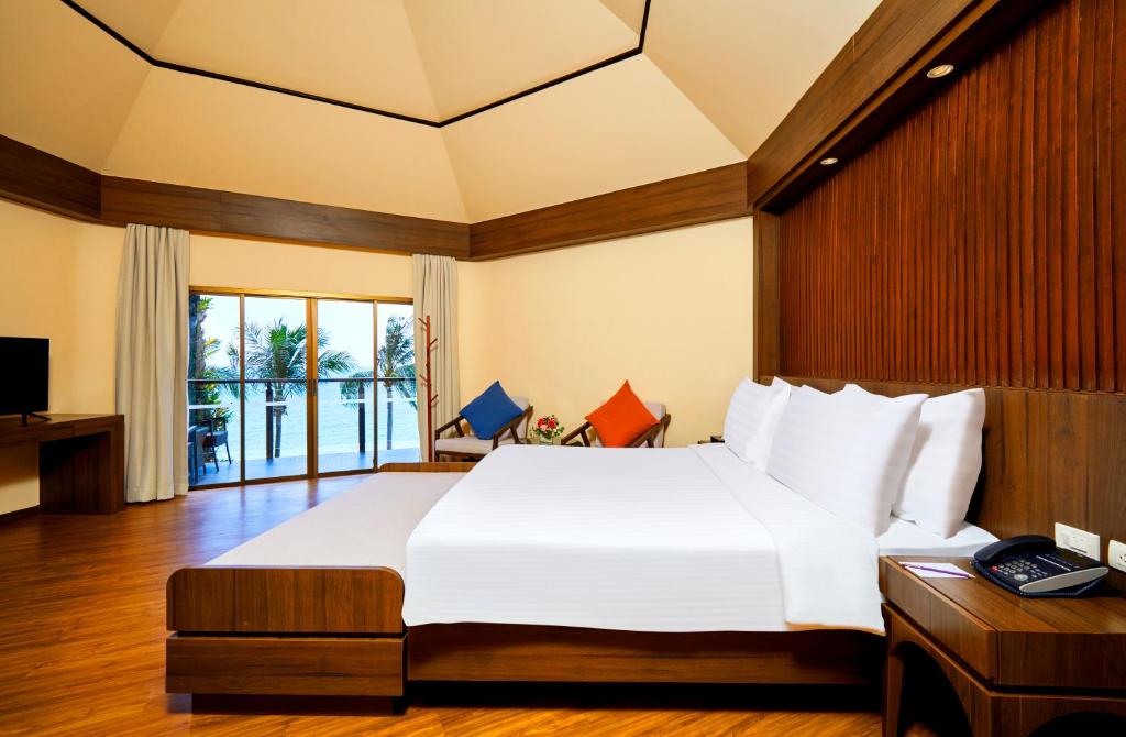 Mūsdienīgs viesnīcas numurs ar plašu gultu un koka interjeru, kas piedāvā skatu uz palmu dārzu un jūru. Numurā ir televizors un komfortabla atpūtas zona ar krēslu un galdiņu.