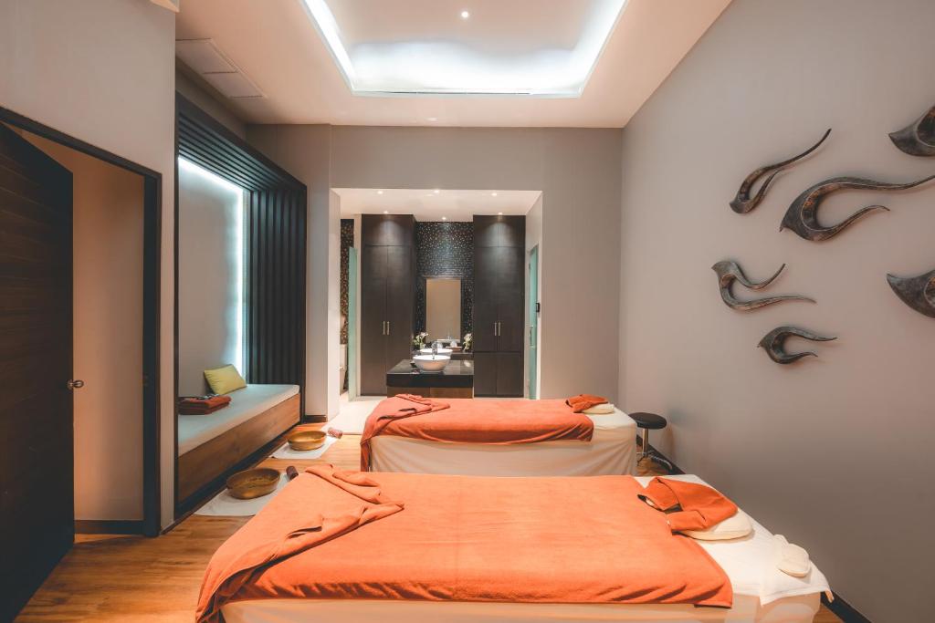 Mūsdienīgs spa telpa ar divām masāžas gultām un relaksējošu interjeru, kas ietver siltas krāsas un dekoratīvas detaļas. Ideāla vieta atpūtai un labsajūtai.