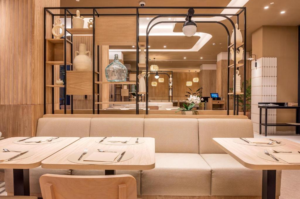 Mūsdienīga restorāna iekārtojums ar koka un stikla elementiem, kas radīts relaksējošai atmosfērai. Mīksta dīvāna un elegantas galdiņu kompozīcijas piesaista apmeklētāju uzmanību.