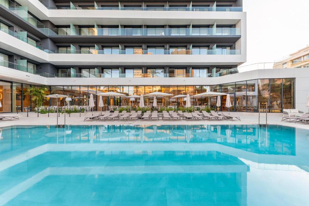 Mūsdienīgs viesnīcas komplekss ar baseinu un saules atpūtas zonu, kas nodrošina relaksējošu atmosfēru. Terase ar šezlongiem un saulessargiem, kas piešķir viesnīcas ainavai pievilcību.