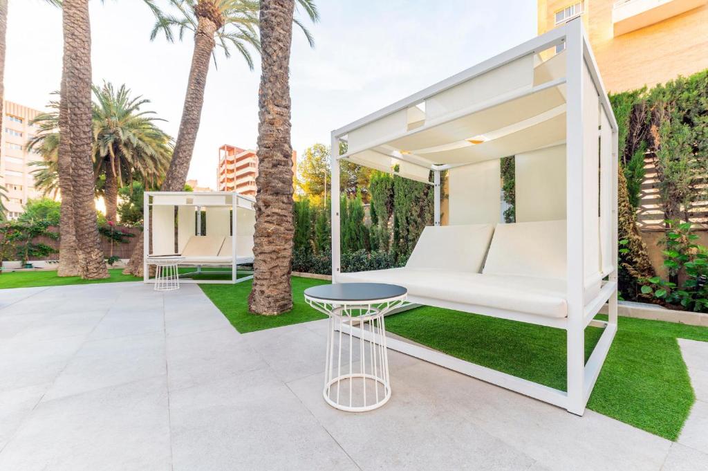 Mūsdienīga atpūtas zona ar baltām nojumejām un palmām, kuras ieskauj zaļā zāle un akmens segums. Ideāla vieta relaksācijai un komfortam.