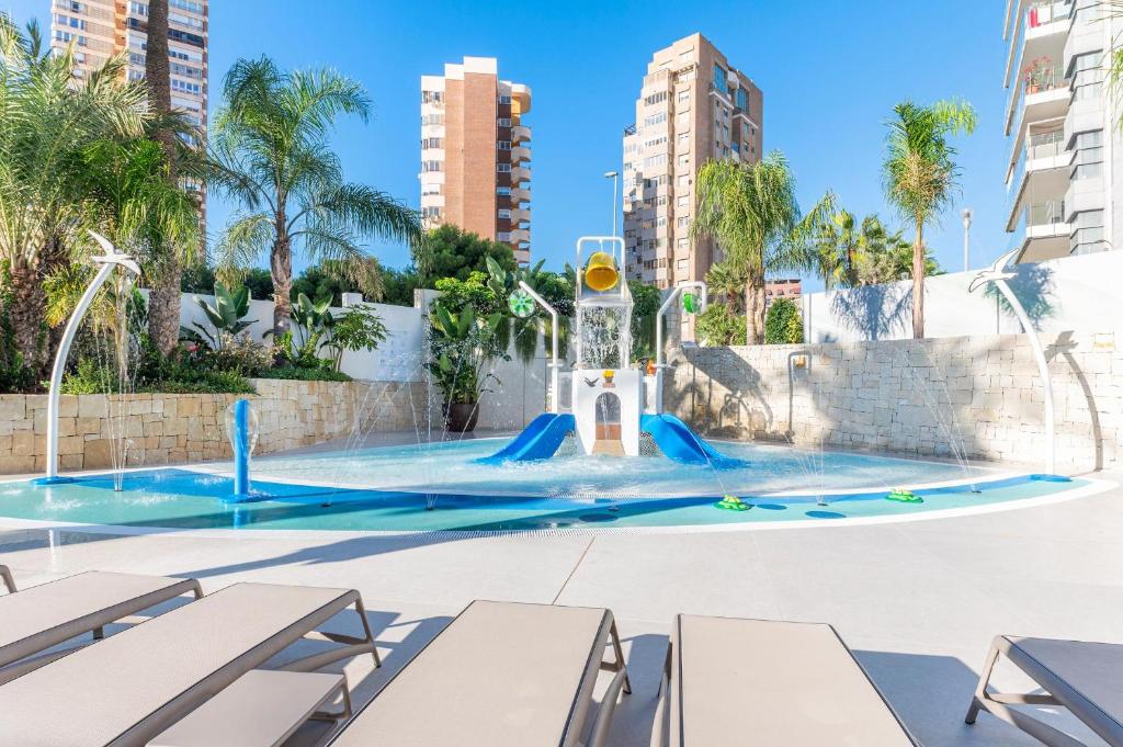 Bērnu ūdens atrakciju parks ar slidkalniņu un strūklakām, ko ieskauj zaļumi un augstceltnes. Ideāla vieta atpūtai un izklaidei saulainā dienā.