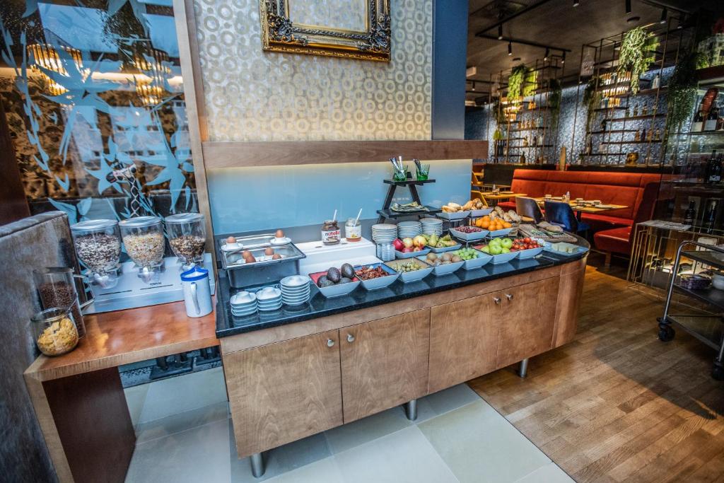 Broka un augļu bufete modernā restorānā ar dažādiem ēdieniem, tostarp graudaugiem, jogurtu un svaigiem augļiem. Interjers ir stilīgs un aicinošs.