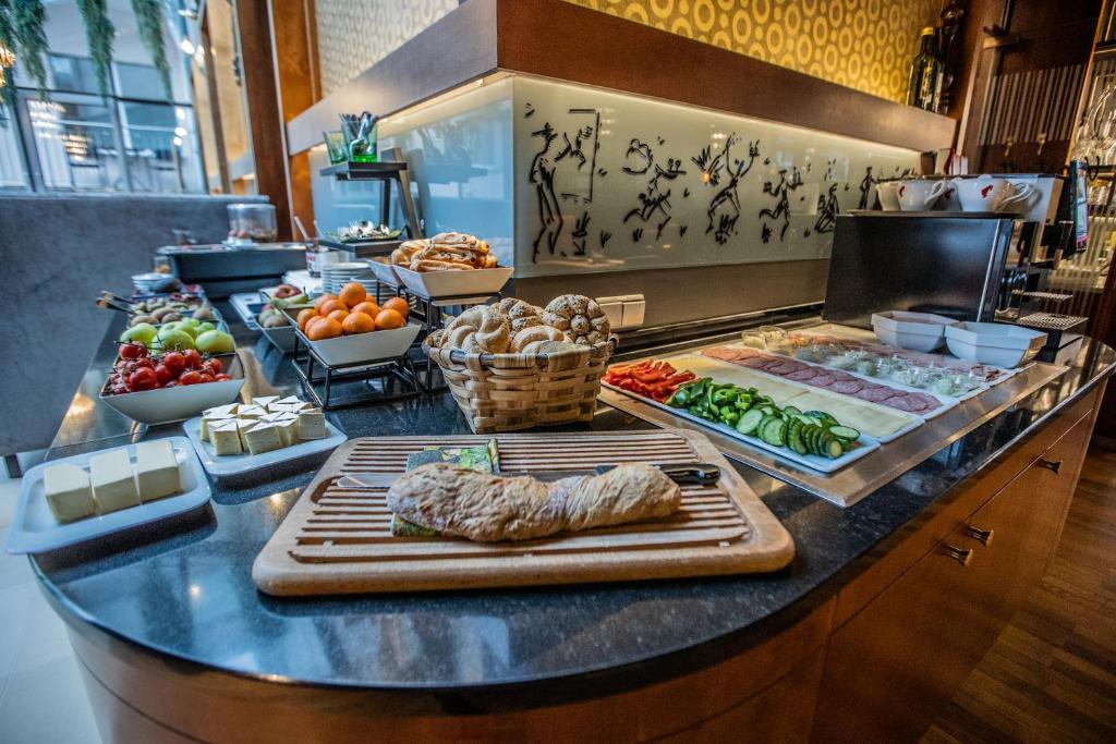 Brokastu bufete ar dažādiem augļiem, maizi, sieru un gaļu, izkārtota stilīgā restorānā. Bagātīgs ēdienu klāsts, kas piedāvā veselīgas un garšīgas izvēles.