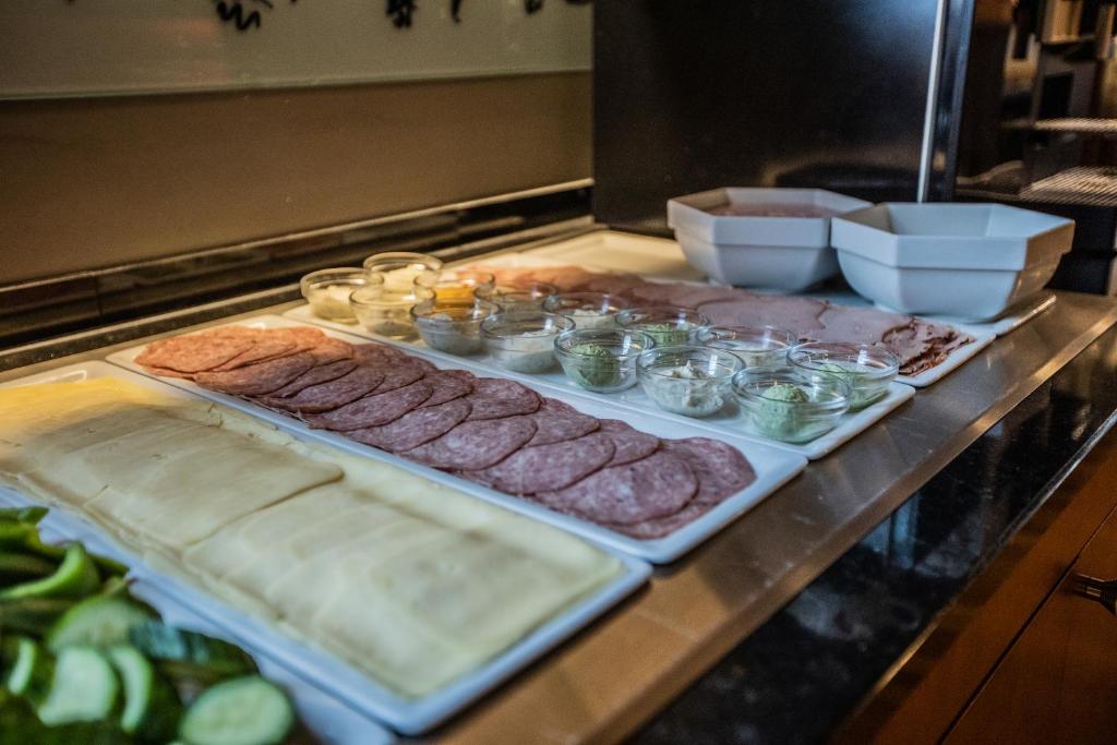 Svaigu sastāvdaļu izvēle uz galda, kas ietver dažādu gaļu, sieru un mērces, ideāli piemērota sviestmaizēm vai uzkodām.