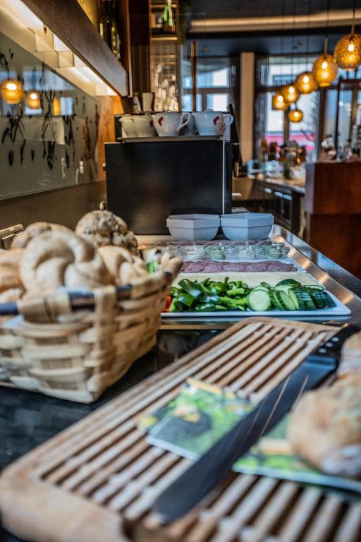 Brokastu bufete ar svaigiem dārzeņiem, maizēm un traukiem, kas izvietoti uz galda modernā restorānā. Izteiksmīga atmosfēra ar siltām gaismām un gaumīgu interjeru.