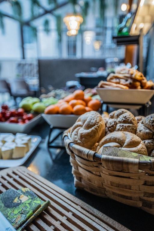 Svaigu maizes izstrādājumu un augļu bufete, kurā redzami dažādi maizes grozi un krāsaini augļi, kas izvietoti uz melna galda.