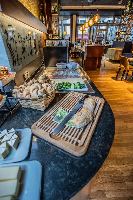 Broku galda klāšana ar maizēm, dārzeņiem un siera šķēlēm, kas atrodas modernā restorānā. Interjers ar koka grīdu un stilīgām lampām.