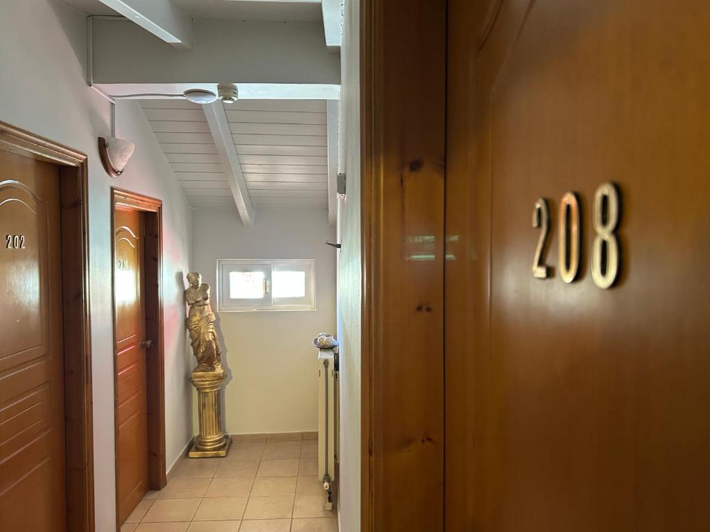 Korridors ar numuriem 202 un 208, kurā redzama statuja un gaiša apgaismojuma atmosfēra.