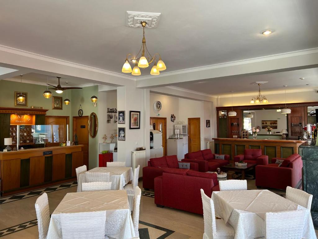 Mūsdienīgs viesnīcas reģistratūras un atpūtas telpas interjers ar sarkaniem dīvāniem un baltiem galdiem. Gaismas ķermeņi un dekoratīvi elementi rada patīkamu atmosfēru.