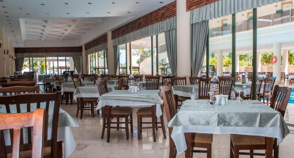 L'ancora Beach Hotel restorāns ar gaišām telpām un elegantiem galdiem.