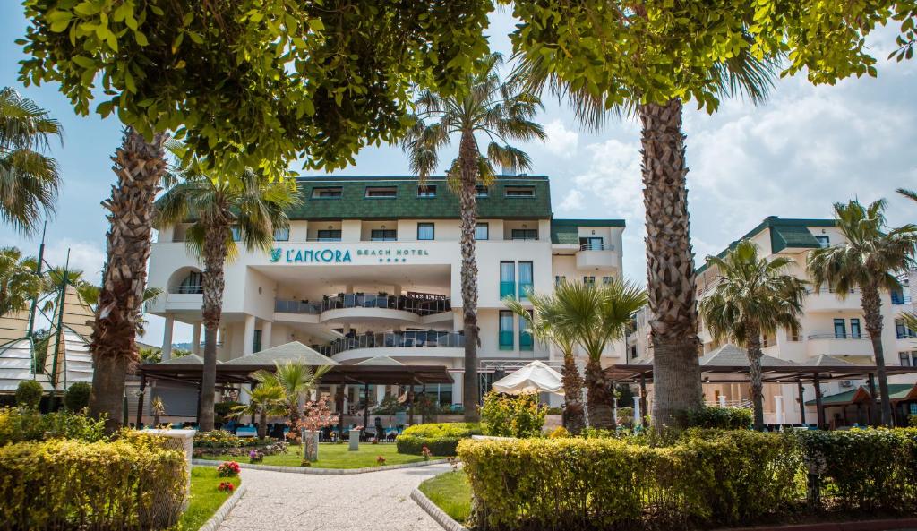L'ancora Beach Hotel priekšpuse ar palmām un dārzu