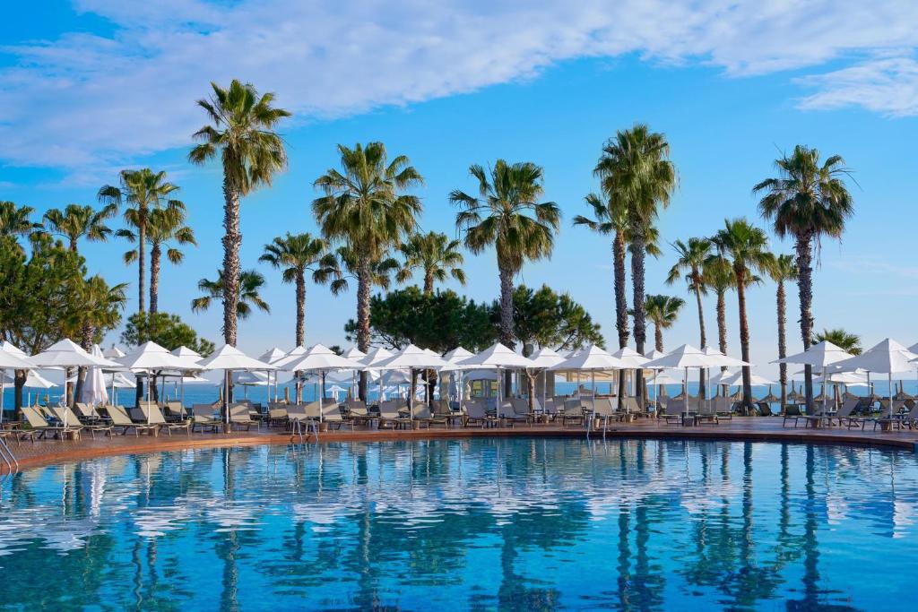 Viesnīcas Voyage Sorgun peldbaseins ar palmiem un sauļošanās krēsliem