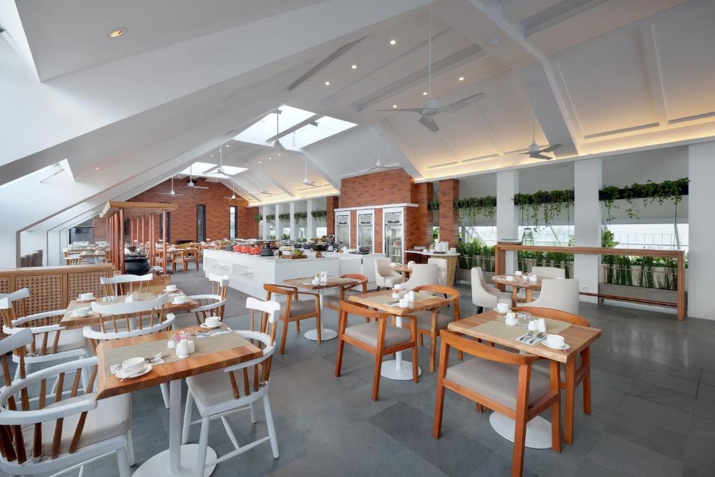 Gaišs un mūsdienīgs restorāns Jambuluwuk Oceano Seminyak ar koka mēbelēm.