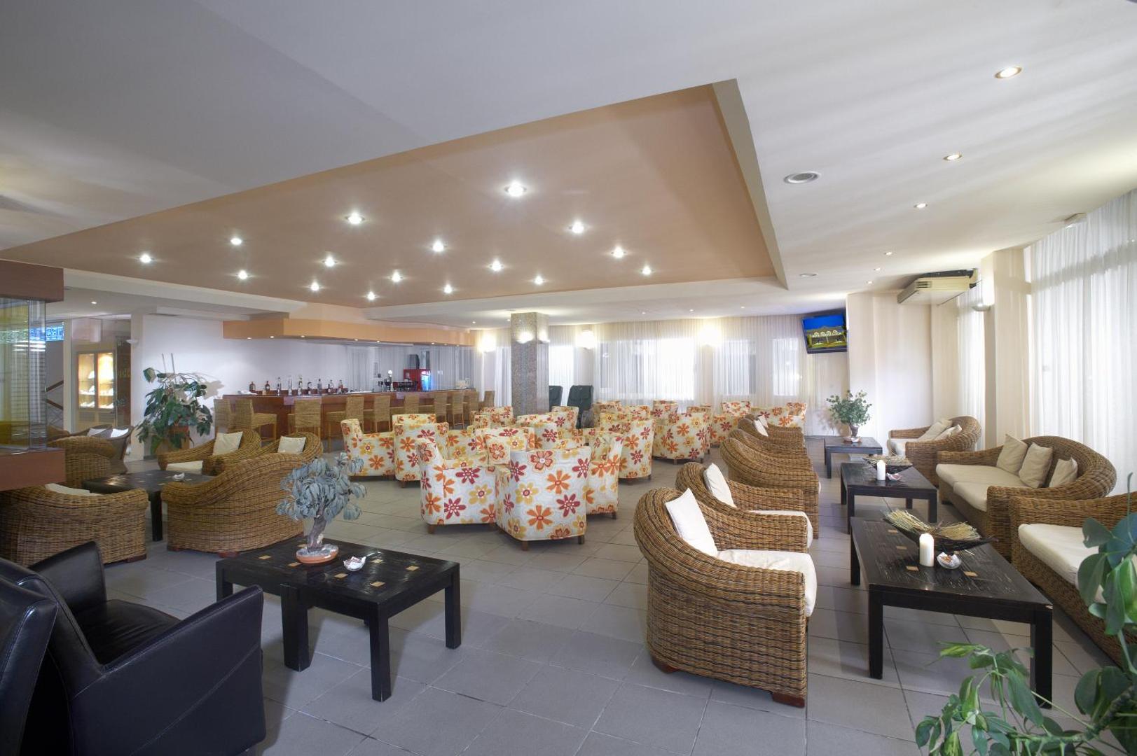 Portes Beach Hotel lobby bārs un atpūtas zona ar pītiem krēsliem un krāsainiem atpūtas dīvāniem viesu ērtībām