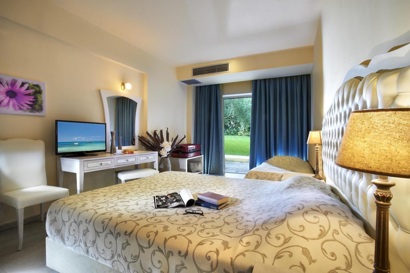 Portes Beach Hotel numurs pirmajā stāvā ar tiešu izeju uz dārzu Halkidiki — divguļamā gulta, rakstāmgalds un zila interjera akcenti
