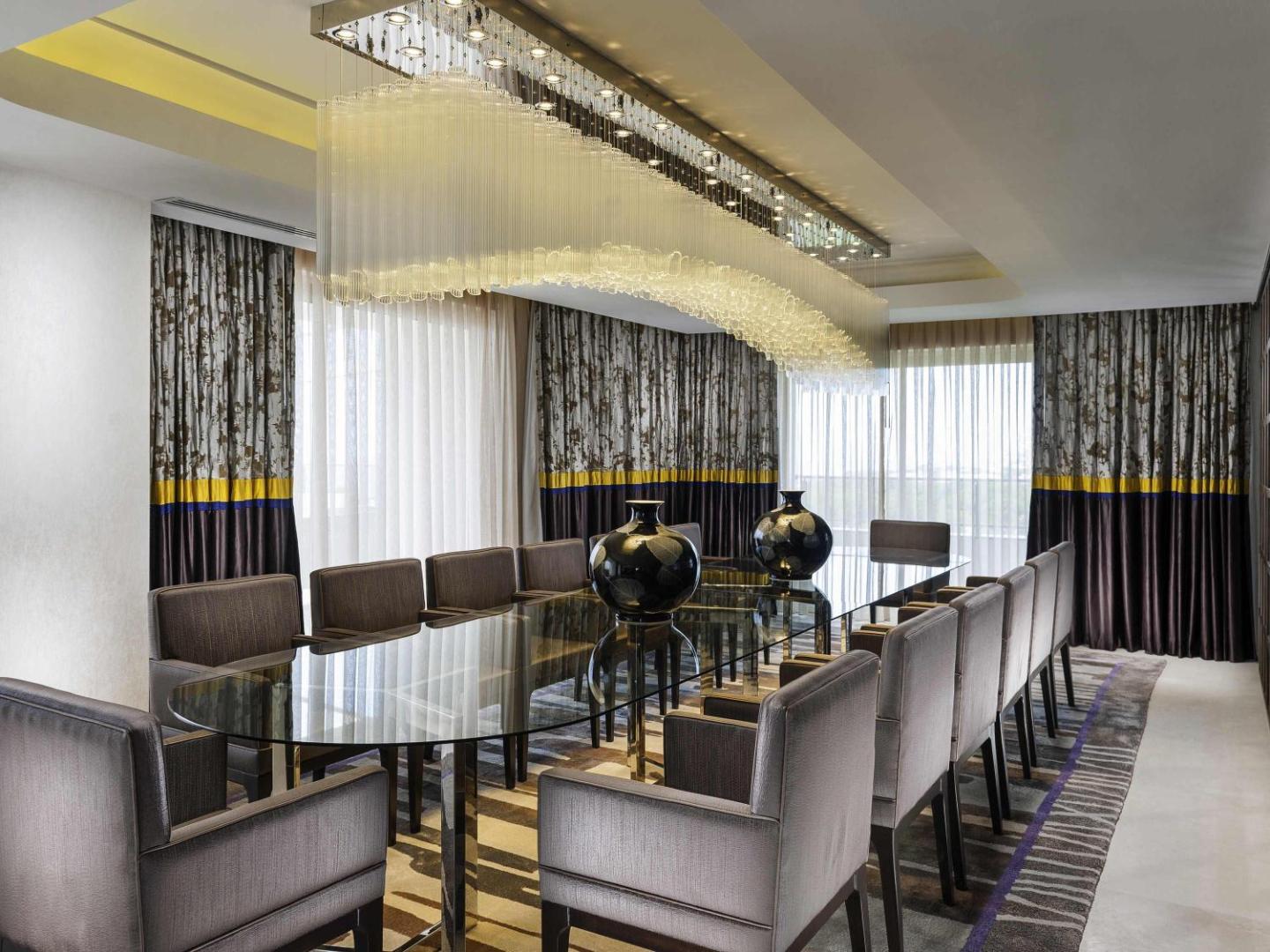 Rixos Premium Belek eleganta konferenču vai pusdienu zāle ar garu stikla galdu, greznu lustru un dizaina elementiem