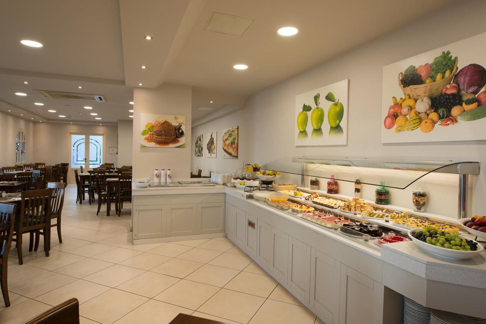 Viesnīcas restorāna bufetes zona ar plašu desertu, kūku un augļu izvēli.