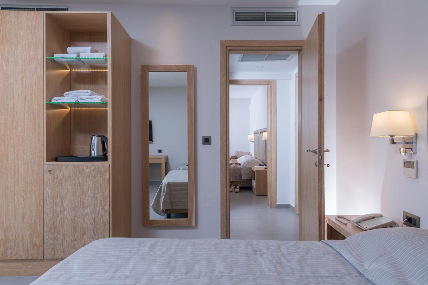 Skats uz numura interjeru ar koka mēbelēm, spoguli un atvērtām durvīm.