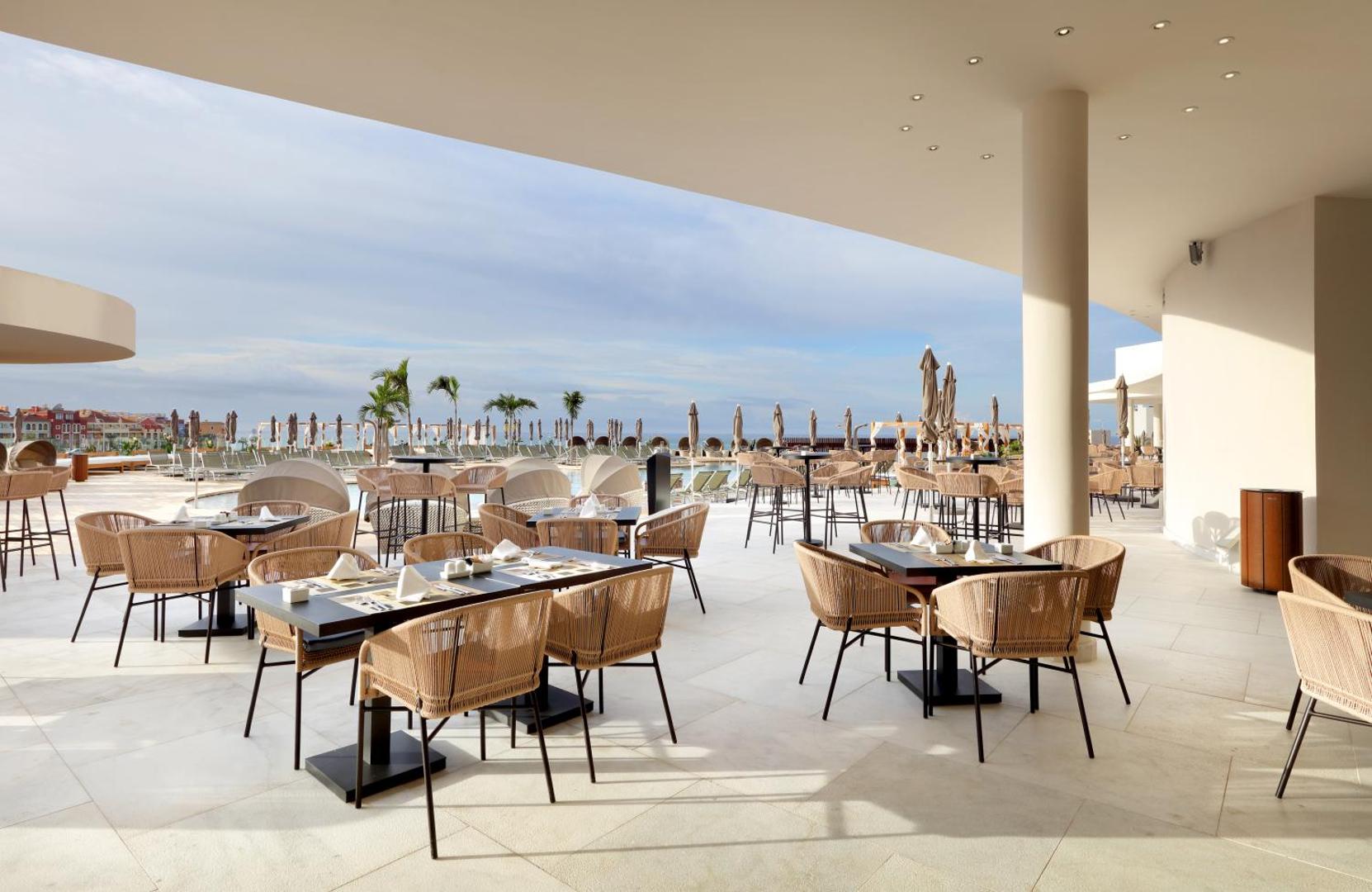 Hard Rock Hotel Tenerife restorāna āra terase ar modernām mēbelēm un skatu uz kūrorta teritoriju un okeānu