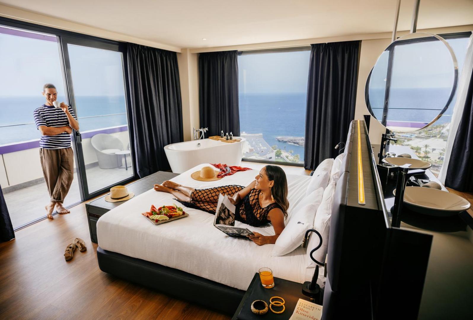 Moderns Hard Rock Hotel Tenerife numurs ar panorāmas logiem, skatu uz okeānu un vannu pie loga.