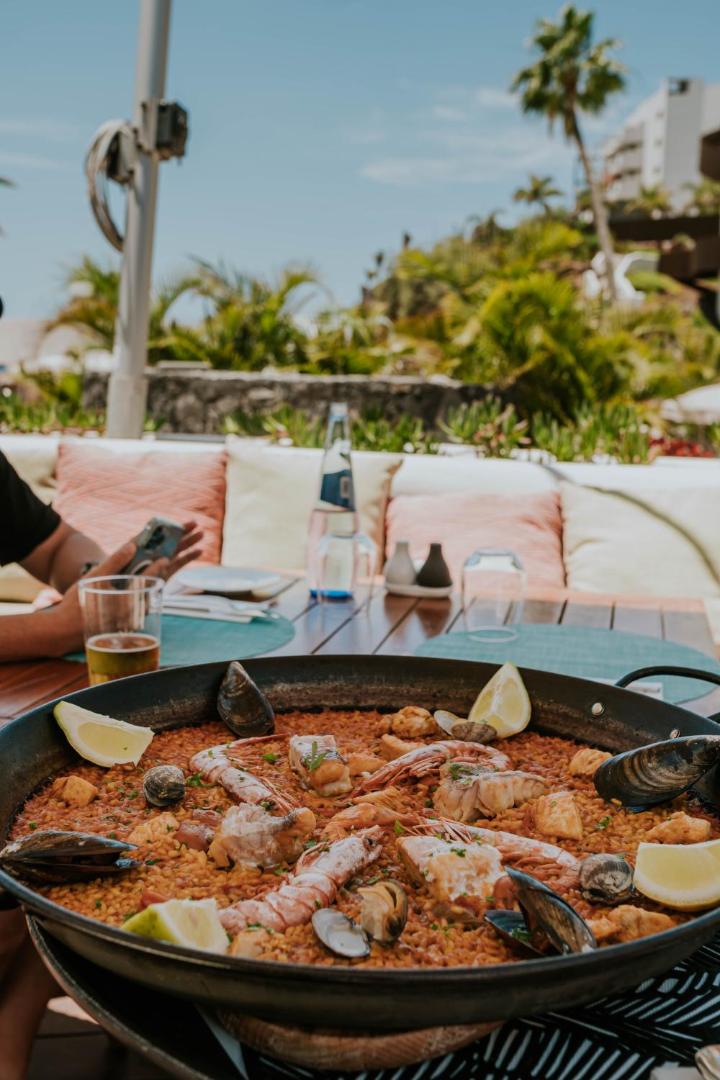 Tradicionāla spāņu paelja ar jūras veltēm un citronu šķēlītēm Hard Rock Hotel Tenerife restorāna āra terasē Tenerifē.