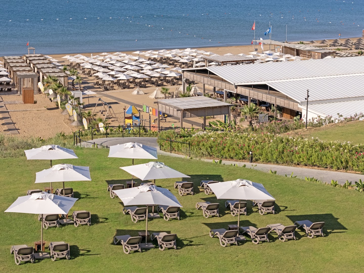 Jacaranda Luxury Resort plašā pludmales zona ar smiltīm, saulessargiem, bērnu rotaļu laukumu un restorānu piekrastē.