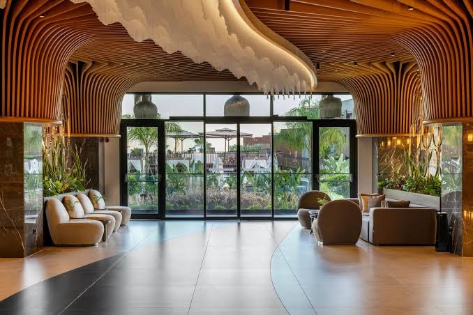 Jacaranda Luxury Resort lobby zona ar unikālu koka griestu dizainu, ērtiem atpūtas krēsliem un skatu uz dārzu