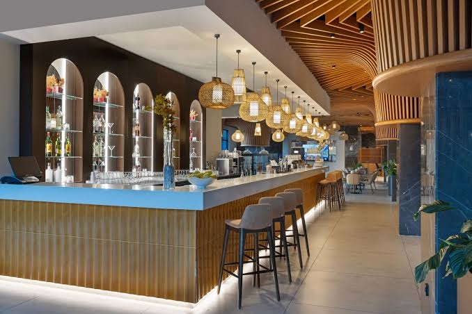 Jacaranda Luxury Resort stilīgais bārs ar koka apdari, moderniem bāra krēsliem un siltu apgaismojumu vakara stundās