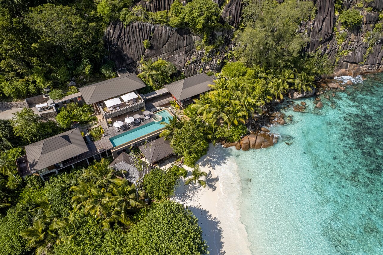 Four Seasons Resort Seychelles villas un baseins piekrastē ar tirkīzzilu ūdeni.