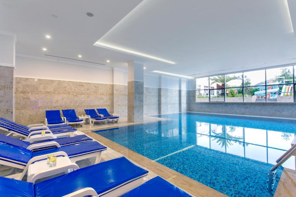 Iekštelpu baseins ar zilo sauļošanās krēslu rindu Kemer Dream Hotel.