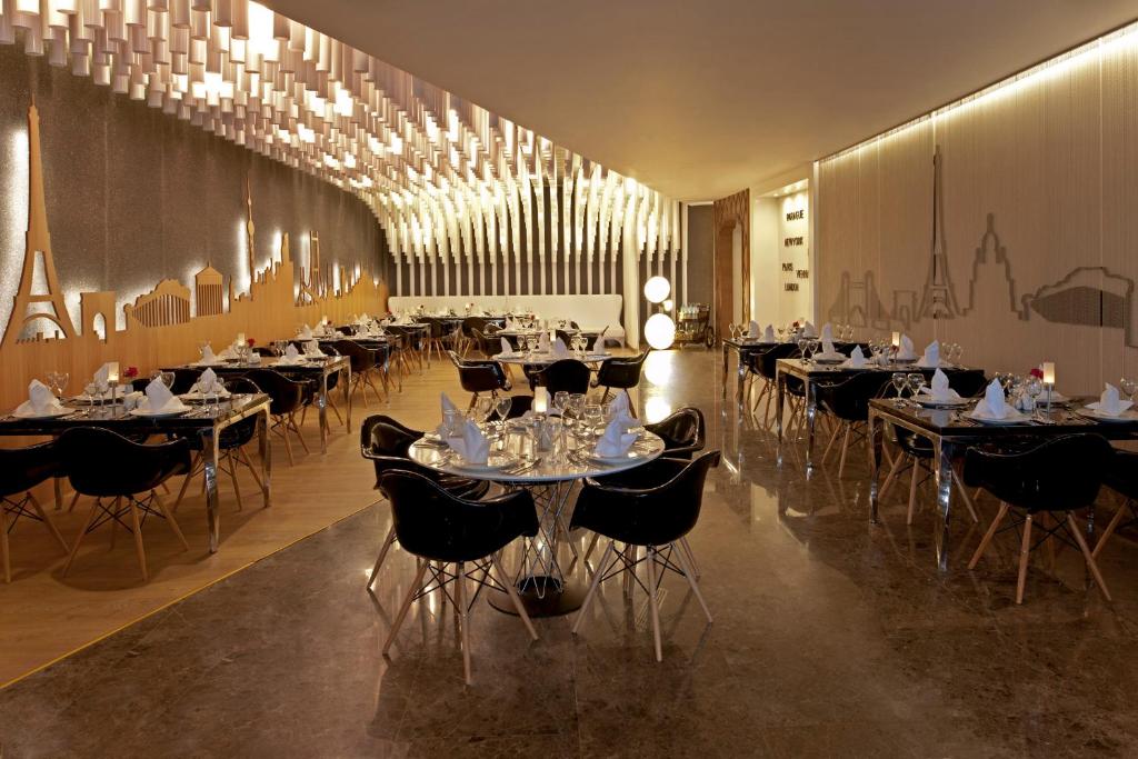 Elegantā restorāna interjers Delphin Imperial Hotel, ar dizaina elementiem un galdniem.