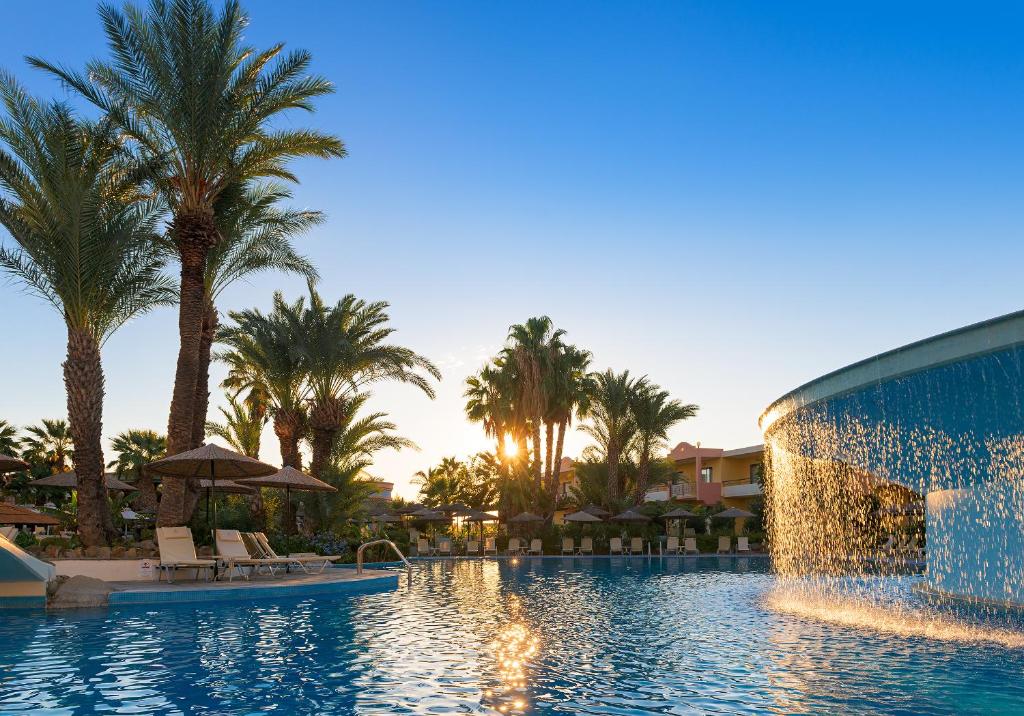 Atrium Palace Thalasso Spa Resort And Villas baseins ar palmu kokiem un saulrietu
