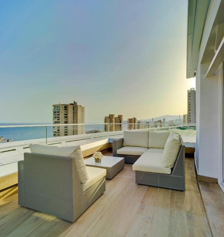 Mūsdienīgs terases dizains ar komfortablu dīvānu un skatu uz pilsētas ainavu un jūru. Ideāla vieta atpūtai un relaksācijai saulrietā.