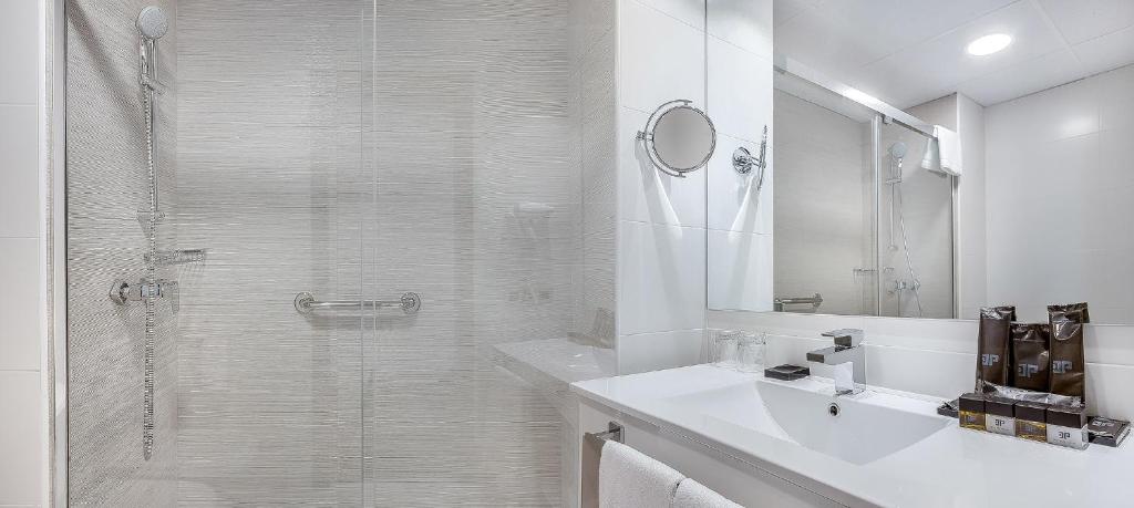 Mūsdienīgs un elegants vannas istabas interjers ar dušu, baltiem flīzēm un mūsdienīgu izskatu. Uz galda redzami higiēnas piederumi un dvieļi, kas piešķir komfortu un eleganci.