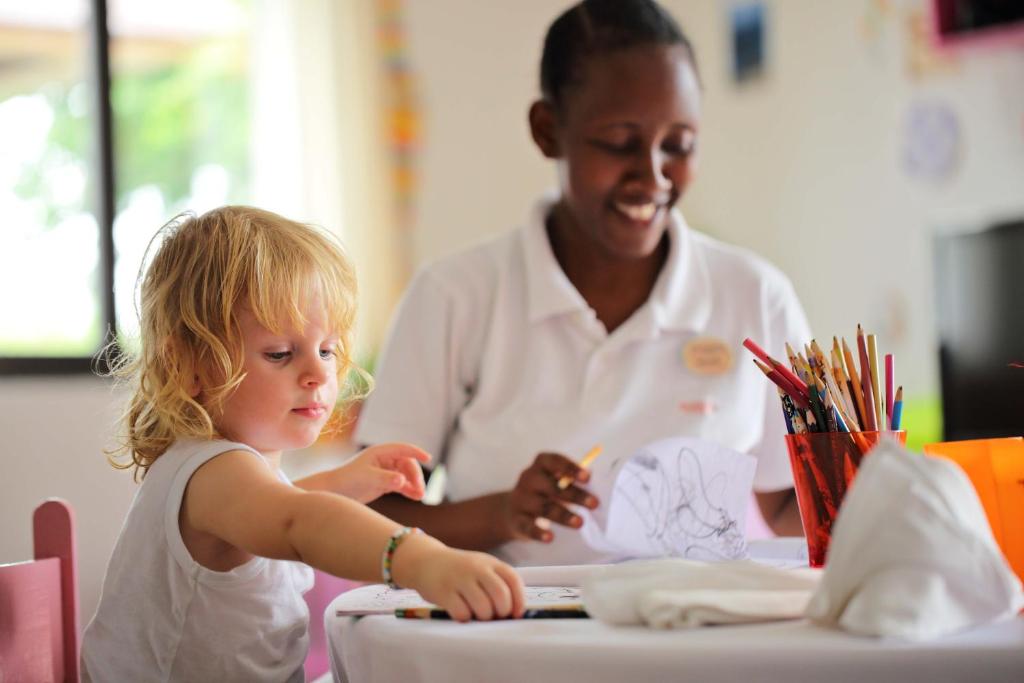 Bērns zīmē ar auklīti viesnīcā The Residence Zanzibar.