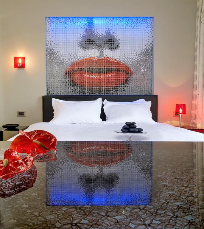 Mūsdienīga guļamistaba ar mozaīkas mākslas darbu un elegantu gultu.