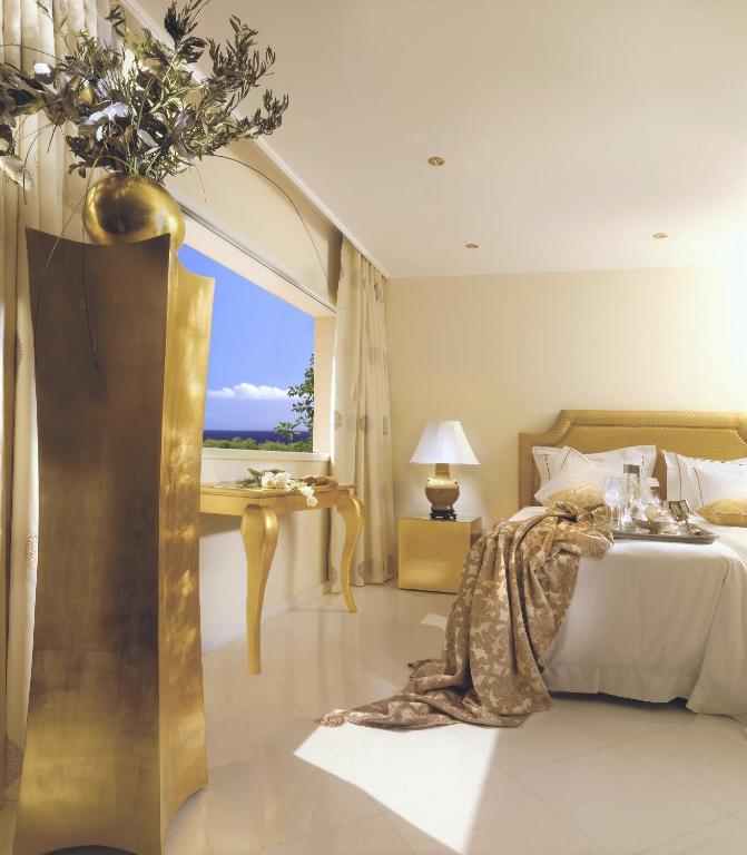 Elegants guļamistabas interjers ar zelta akcentiem un skatu uz jūru.