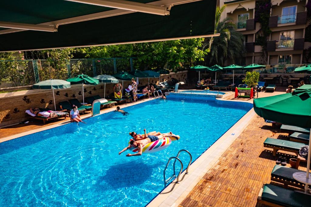 Viesnīcas Ambassador Plaza Hotel baseins ar apmeklētājiem un sauļošanos panoramic view with beach and pools