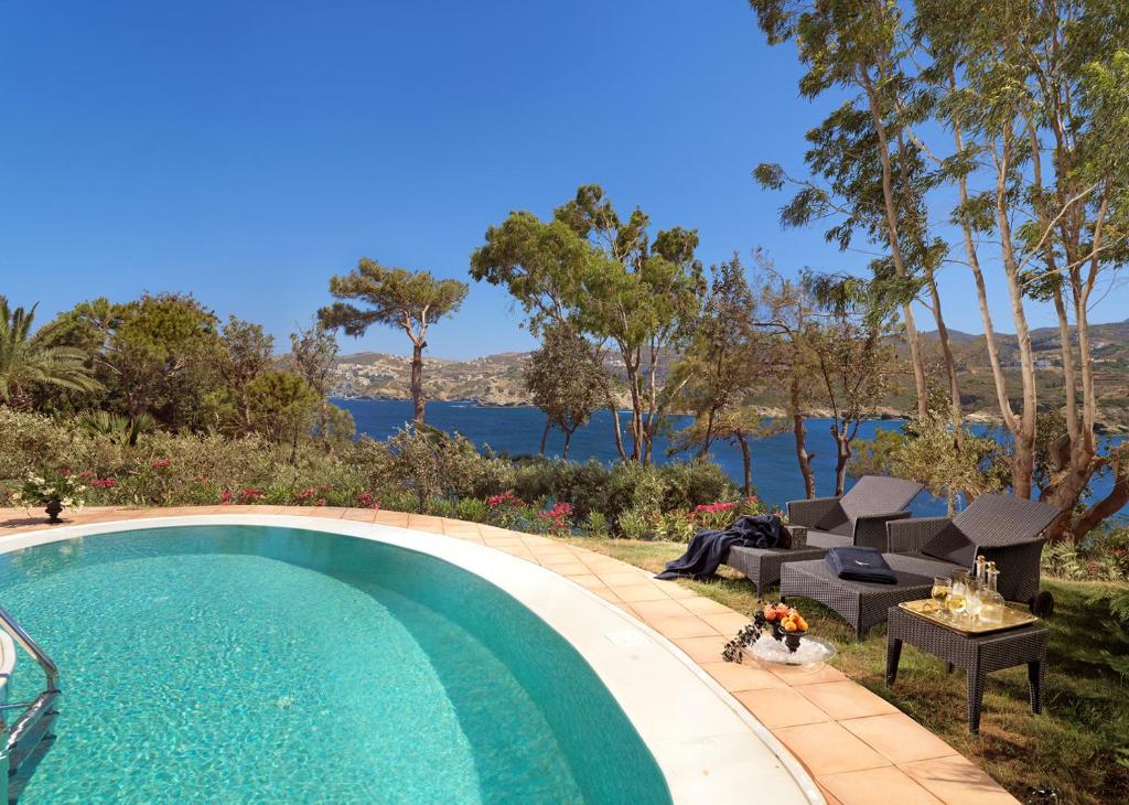 Luksusa viesnīcas baseins ar skatu uz jūru un atpūtas krēsliem.