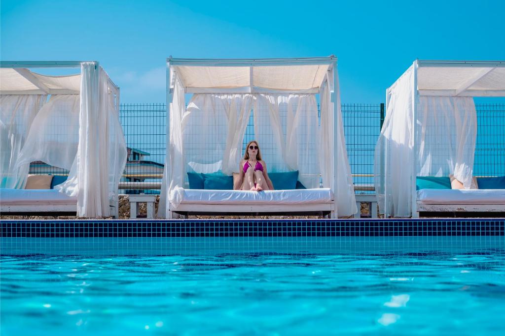 Sieviete atpūšas pie baseina Michell Hotel & Spa luksusa gultās.